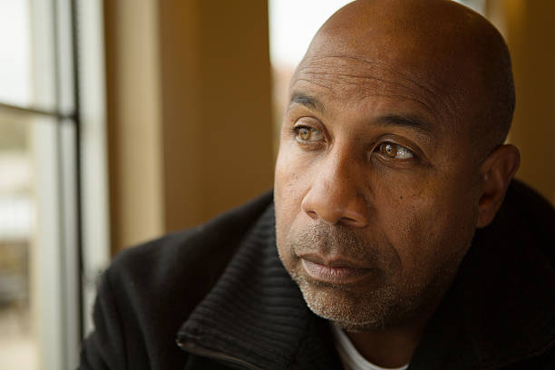 Man looking out the window with a somber expression