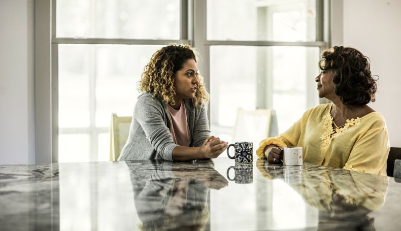 A daughter and mother share a conversation over coffee.