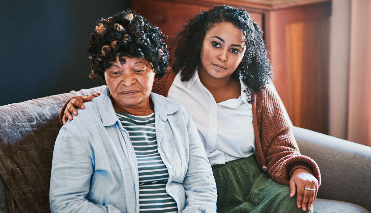 A young woman comforting her mother while sitting on a couch